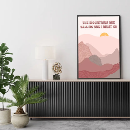 ForWalls.eu - Plakat Mountain Calling - Minimalist mountain poster in pink and rust tones with layered hills and sun, framed in black on a white wall. - góry, minimalistyczny, natura, plakat